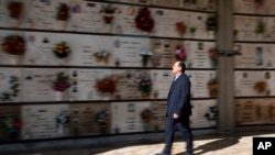 Rev. Mario Carminati walks in a cemetery in Seriate, near Bergamo, Italy, Sunday, Sept. 27, 2020. As the world counts more than 1 million COVID victims, the quiet of everyday life and hum of industry has returned to Bergamo. (AP Photo/Antonio Calanni)