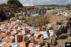 Cambodian police officers prepare to destroy counterfeit products at a dump site in Choeung Ek village on the outskirts of Phnom Penh, July 7, 2016.