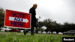 FILE - A woman arrives at a polling station in Lark Community Center as early voting for midterm elections started, in McAllen, Texas, Oct. 22, 2018.
