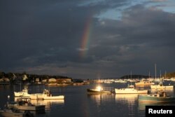 A rainbow is seen above lobster boats in the harbor of Stonington, Maine, July 4, 2017.