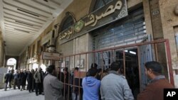 Libyan citizens queue outside a bank to get cash, in Benghazi, Libya