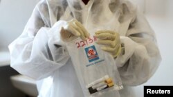 FILE - A health worker holds a COVID-19 sample collection kit of a vaccine trials' volunteer, after they were tested and take part in human clinical trial for potential vaccines at the Wits RHI Shandukani Research, in Johannesburg, Aug. 27, 2020.