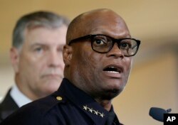 FILE - Dallas police chief David Brown, front, and Dallas mayor Mike Rawlings, rear, talk with the media during a news conference, in Dallas.