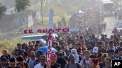 Migrantes que caminan por la carretera llevan una cruz que dice en español "Cristo Resucitado" durante la Semana Santa mientras avanzan por Tapachula en el estado mexicano de Chiapas, el lunes 25 de marzo de 2024. 