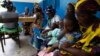 FILE - Women holding children wait for a medical examination at the health center in Gbangbegouine, Ivory Coast