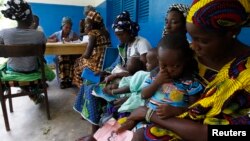 FILE - Women holding children wait for a medical examination at the health center in Gbangbegouine, Ivory Coast