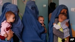 FILE - In this Aug. 26, 2019 photo, mothers hold their babies suffering from malnutrition as they wait at a UNICEF clinic in Jabal Saraj, north of Kabul, Afghanistan.