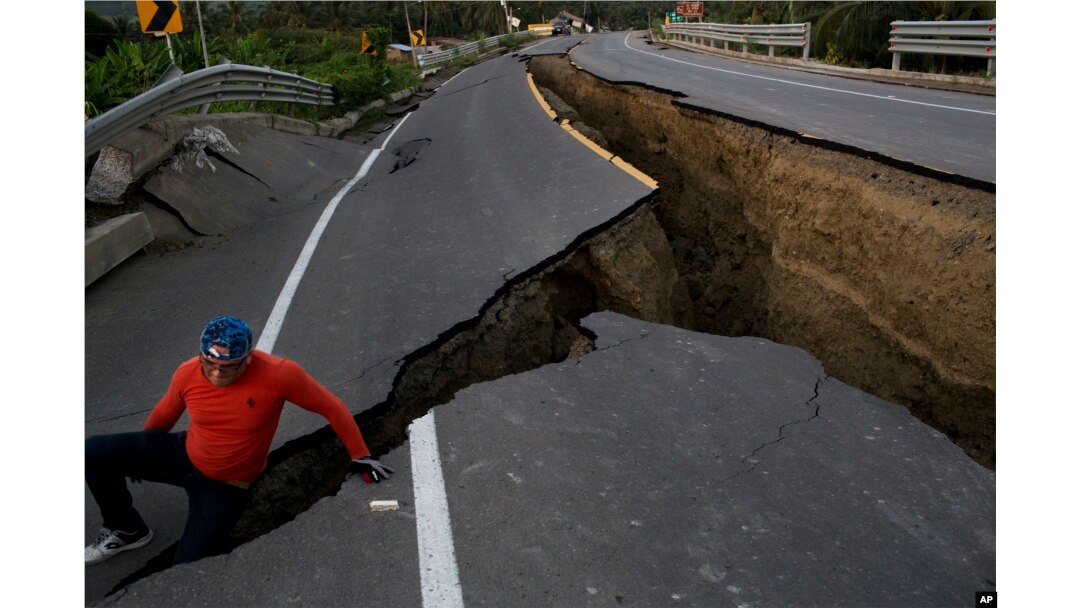 A man jokes around after taking some pictures of a section of highway that collapsed due to a 7.8-magnitude earthquake, in Chacras, Ecuador, April 19, 2016.