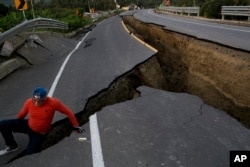 A man jokes around after taking some pictures of a section of highway that collapsed due to a 7.8-magnitude earthquake, in Chacras, Ecuador, April 19, 2016.
