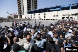 FILE - Supporters of prominent Iraqi Shi'ite cleric Muqtada al-Sadr try to remove a barbed wire fence as they break the checkpoint on the bridge leading to Baghdad's heavily fortified Green Zone in Iraq, March 18, 2016.