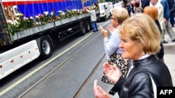 Bosnian Muslims, citizens of Sarajevo, pray near a truck, carrying the remains of 35 newly identified victims of Srebrenica massacre, while it makes a short stop in Sarajevo city center, July 9, 2018.