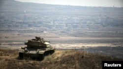 Tank Israel terlihat menghadap Quneitra, Suriah, terlihat di latar belakang.dekat garis perbatasan gencatan senjata antara Israel dan Suriah, di Golan Heights yang dikuasai Israel (21/8).