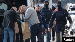 Police look at bags of evidence material during a search in the Brussels borough of Schaerbeek following Tuesday's bombings in Brussels, Belgium, March 25, 2016. 