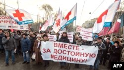 FILE - Protesters carry a banner reading "Together for decent medical care!" as they march in a street in Moscow, Russia, Nov. 30, 2014.