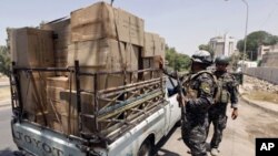 Policemen search a vehicle at a checkpoint on Baghdad's Abu Nawas street. About 15 people were wounded in several bomb attacks that occurred in the Iraqi capital on Monday, June 20, 2011