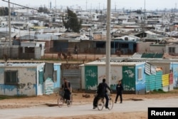 FILE - Syrian refugees ride their bicycles in the Zaatari refugee camp near the border city of Mafraq, Jordan, Feb. 1, 2020.