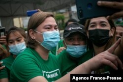 FILE - This photo taken on Nov. 9, 2021 shows Sara Duterte--Carpio (L), mayor and daughter of outgoing Philippines President Rodrigo Duterte, posing for a selfie with city hall employees in Davao city, on the southern island of Mindanao.