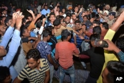 An angry crowd shouts slogans beside the body of a victim of a train accident in Amritsar, India, Oct. 19, 2018.