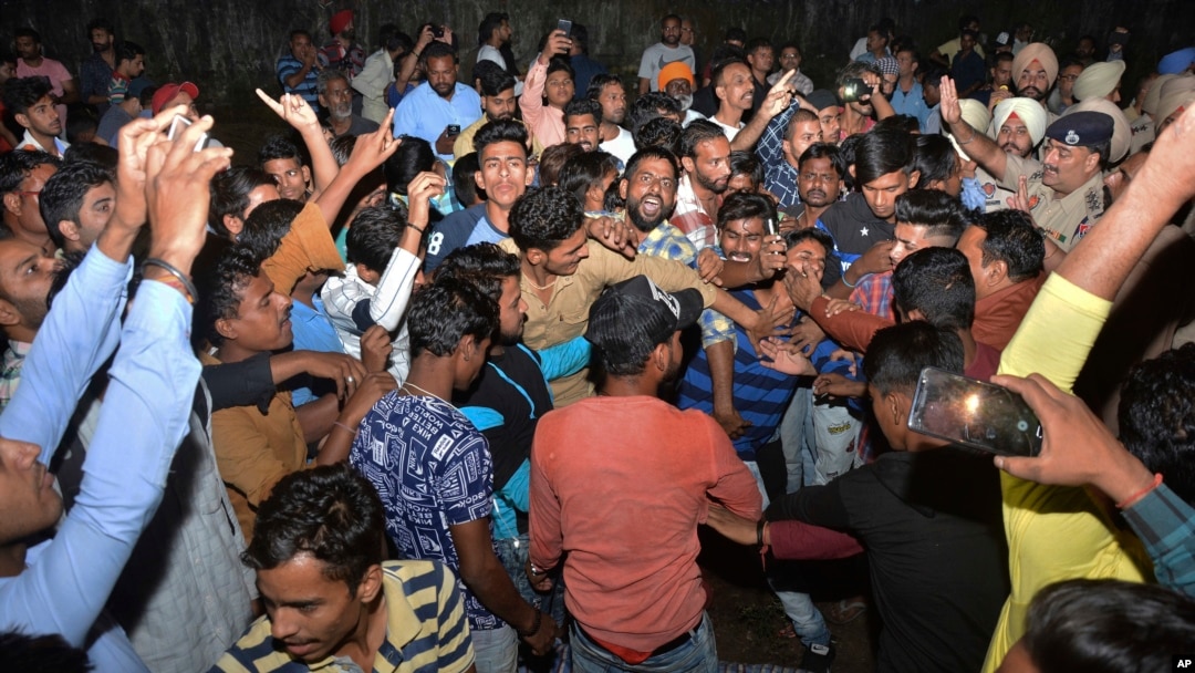 Warga yang marah meneriakkan kekesalannya di samping tubuh korban kecelakaan kereta api di Amritsar, India, 19 Oktober 2018.