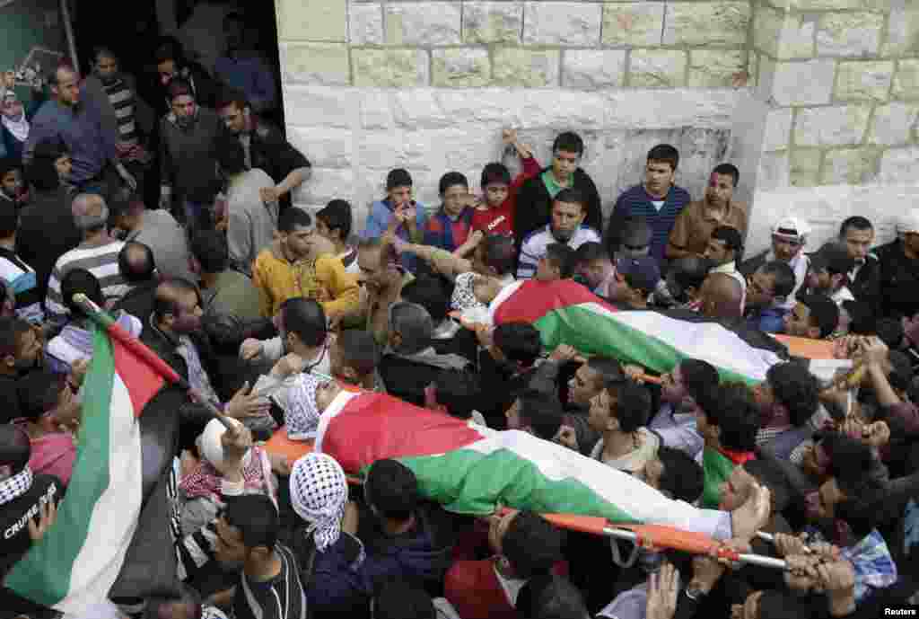 Palestinians carry the bodies of Amer Nassar, 17, and Naji Belbisi, 18, into a mosque during their funeral in the West Bank, April 4, 2013.