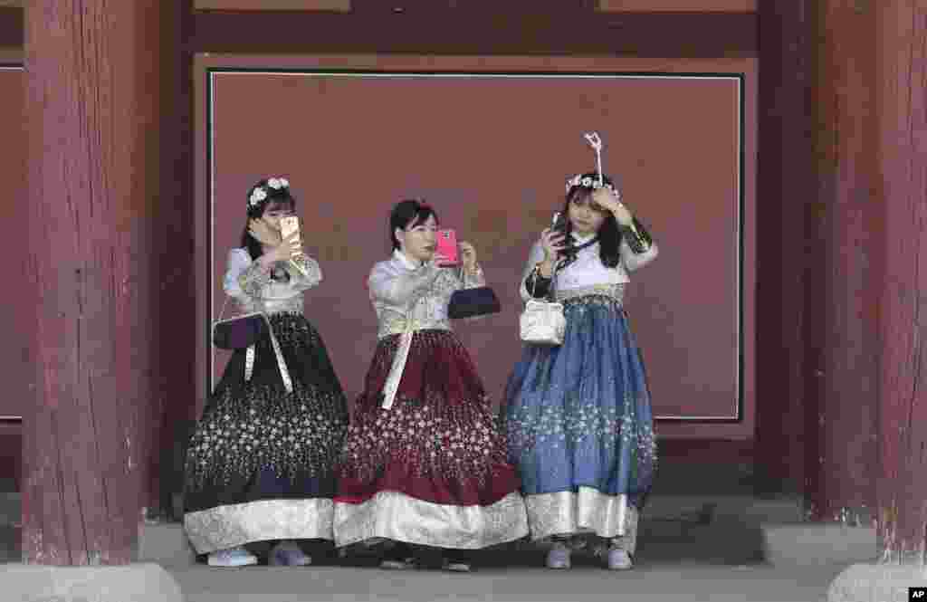 Women dressed in South Korean traditional &quot;Hanbok&quot; attire adjust their hair at the Gyeongbok Palace, the main royal palace during the Joseon Dynasty, in Seoul.