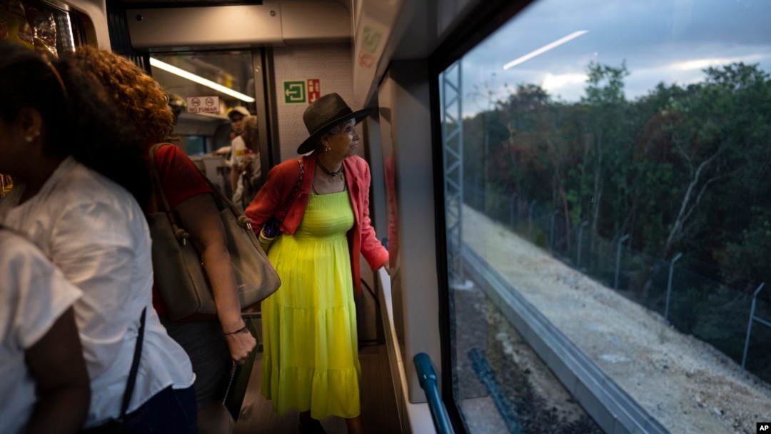 A passenger looks at the passing jungle landscape while traveling on the Maya Train from Cancun to Valladolid, Mexico, March 6, 2024. When it's completed, the high-speed Maya Train will wind around Mexico's southern Yucatan peninsula.