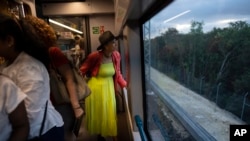 A passenger looks at the passing jungle landscape while traveling on the Maya Train from Cancun to Valladolid, Mexico, March 6, 2024. When it's completed, the high-speed Maya Train will wind around Mexico's southern Yucatan peninsula.