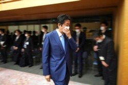 Perdana Menteri Jepang Shinzo Abe membetulkan letak masker wajahnya seusai menggelar konferensi pers di kantor perdana menteri di Tokyo, 4 Mei 2020.