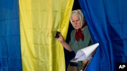 Seorang perempuan keluar dari bilik setelah memberikan suaranya dalam pemilihan presiden di Krasnoarmiisk timur, Ukraina, Minggu, 25 Mei 2014.