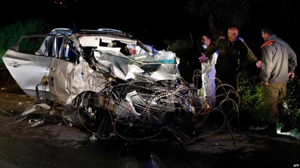 Israeli security forces and forensics experts inspect the destroyed vehicle that was used by a Palestinian assailant in a ramming attack targeting a group of Israeli soldiers near Mevo Dotan in the north of the occupied West Bank, March 16, 2018. 