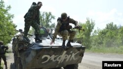 FILE - A Ukrainian serviceman jumps from an armored personnel carrier in Avdeyevka near Donetsk, Ukraine, June 4, 2015. 