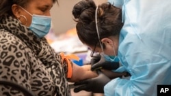 FILE - Registered nurse Stephanie Mundo draws blood during a COVID-19 antibody test at the Abyssinian Baptist Church, May 14, 2020, in the Harlem neighborhood of Manhattan, New York. 