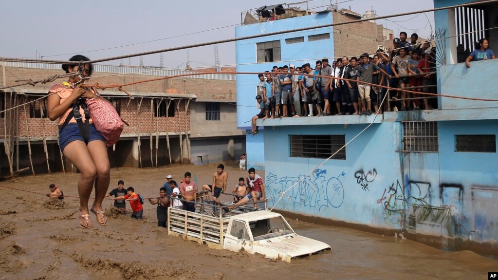 A woman is pulled to safety in a zip line harness in Lima, Peru, March 17, 2017. Intense rains and mudslides over the previous fewer days have wrought havoc around the Andean nation and caught residents in Lima, a desert city of 10 million where it almost never rains, by surprise.