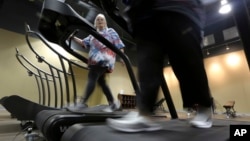 FILE - Gym members use treadmills to warm up for a morning exercise class at Downsize Fitness, in Addison, Texas, Jan. 3, 2013. Researchers in Denmark found that carrying a few extra kilograms might not be as harmful as it was a few decades ago.