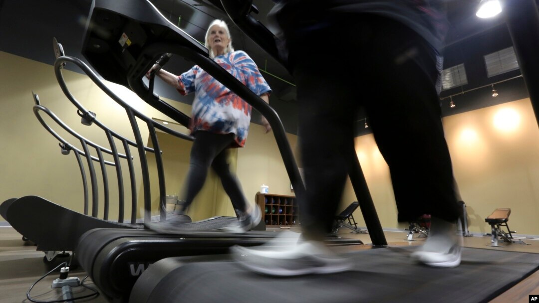 FILE - Gym members use a treadmill to warm up for a morning exercise class at Downsize Fitness, in Addison, Texas, Jan. 3, 2013.