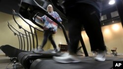 FILE - Gym members use a treadmill to warm up for a morning exercise class at Downsize Fitness, in Addison, Texas, Jan. 3, 2013.