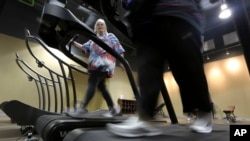 FILE - Gym members use as treadmill to warm up for a morning exercise class at Downsize Fitness, in Addison, Texas, Jan. 3, 2013. 