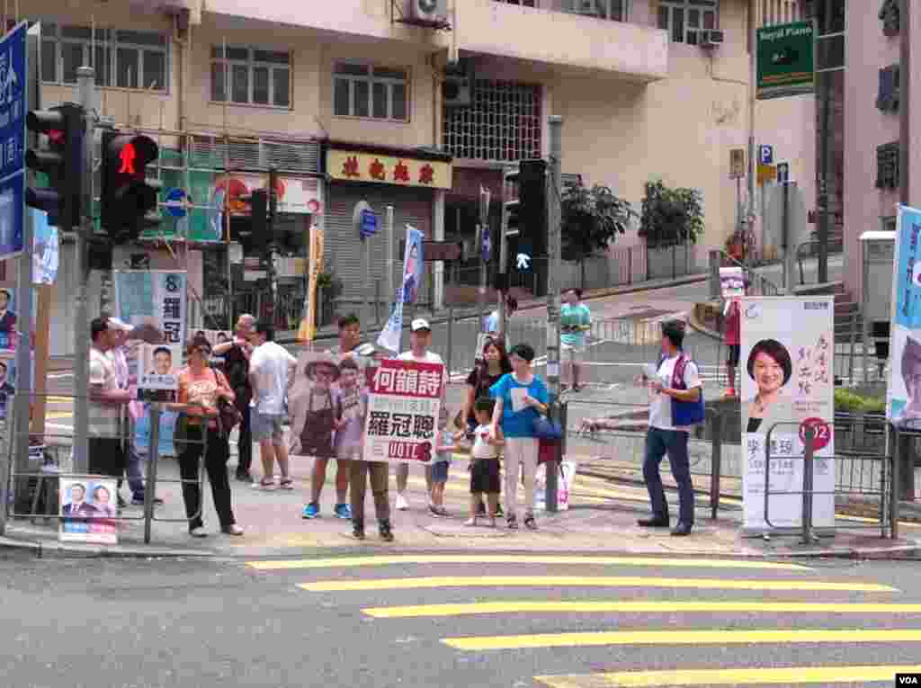 助选义工在路口坚持为各自候选人拉票(美国之音海彦拍摄)