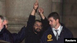 FILE - Ali Charaf Damache, also known by the alias "Black Flag," is accompanied by Irish law enforcement officials as he appears at Waterford District Court to be remanded into custody after being arrested on terrorism charges in Waterford, Ireland, March 13, 2010.