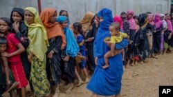 Para pengungsi perempuan Rohingya yang baru tiba di tempat penampungan mereka di Kutupalong, Bangladesh, antri menunggu giliran pembagian bahan bangunan yang didistribusikan oleh badan-badan bantuan di kamp tersebut, Rabu, 13 September 2017. (AP Photo/Dar Yasin)