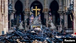 A view of the cross and sculpture of Pieta by Nicolas Coustou in the background of debris inside Notre Dame, in the aftermath of a fire that devastated the cathedral in Paris, France, April 16, 2019. 