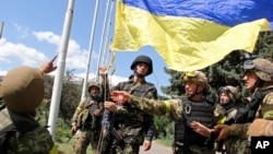 FILE - Ukrainian soldiers and Ukrainian Defense Minister Valery Heletey, third from right, raise a Ukrainian flag in downtown Slovyansk, eastern Ukraine. 