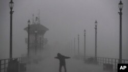 A man struggles against gusty wind and heavy rain as he walks along a pier in Huntington Beach, Calif., Feb. 17, 2017. A major Pacific storm has unleashed downpours and fierce gusts on Southern California, triggering flash flood warnings and other problem