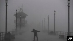 ہنٹنگٹن ساحل پر ایک شخص طوفانی ہواؤں سے گزرنے کی کوشش کر رہا ہے۔