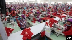 This photo taken on Aug. 30, 2017 shows garment workers sewing clothes in a factory as they wait for visit by Prime Minister Hun Sen outside of Phnom Penh, Cambodia.