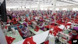 FILE - Garment workers sew clothes in a factory outside Phnom Penh, Cambodia, Aug. 30, 2017. A new government initiative now makes available to them free legal services to help settle disputes with employers. But some see the offer as hollow.