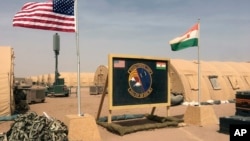 FILE - In this photo taken April 16, 2018, a U.S. and Niger flag are raised side by side at the base camp for air forces and other personnel supporting the construction of Niger Air Base 201 in Agadez, Niger. 