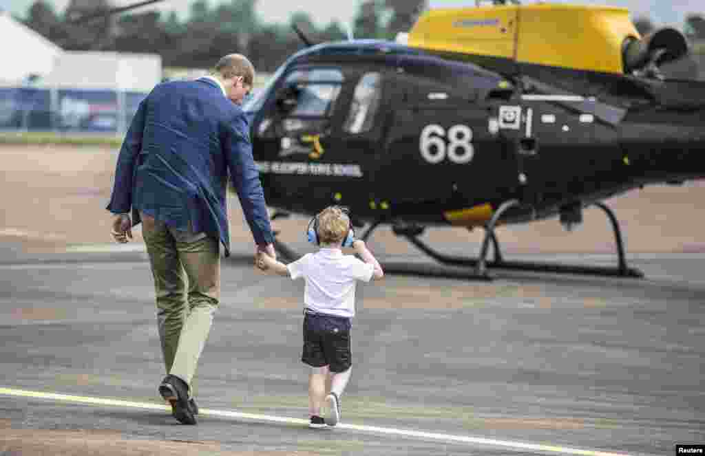 Britain&#39;s Prince George walks with his father Prince William during a visit to the Royal international air show at RAF Fairford.