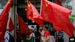 FILE - China supporters march with Chinese national flags during a rally to mark the 18th anniversary of Hong Kong's handover to China, in Hong Kong, July 1, 2015.