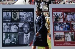 A woman walks past memorial placards for former president Daniel arap Moi, at his state funeral in Nyayo Stadium, in Kenya's capital of Nairobi, Kenya, Feb. 11, 2020.